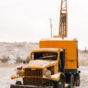 Vintage old crane truck with a hydraulic boom, rusted exterior, and heavy-duty lifting capabilities, parked at a construction site