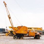 Vintage old crane truck with a hydraulic boom, rusted exterior, and heavy-duty lifting capabilities, parked at a construction site